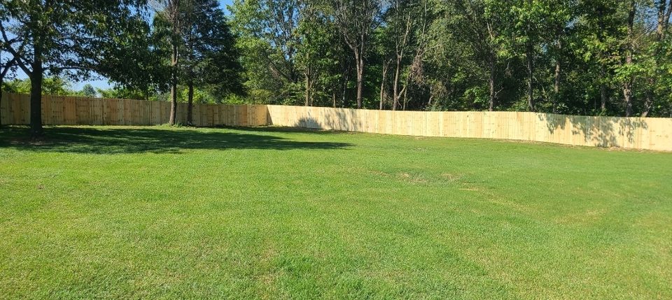 New treated-pine privacy fence around a large lawn in Northwest Arkansas