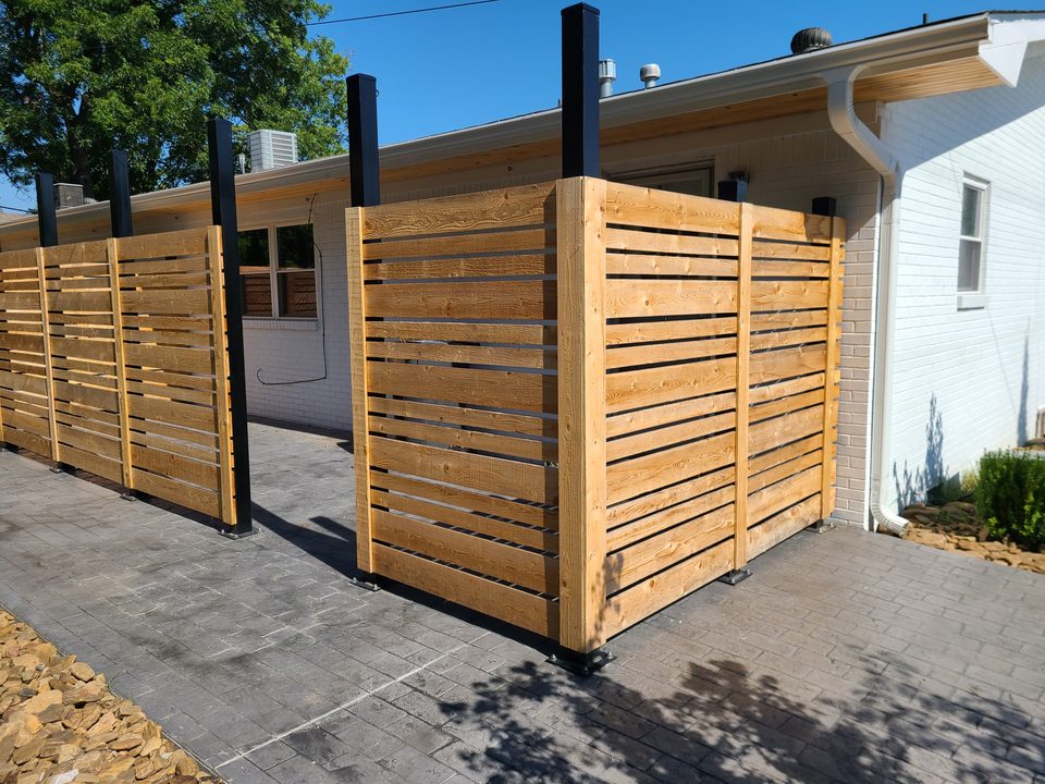 Modern horizontal-slat wood privacy screens with steel posts beside a home in Northwest Arkansas