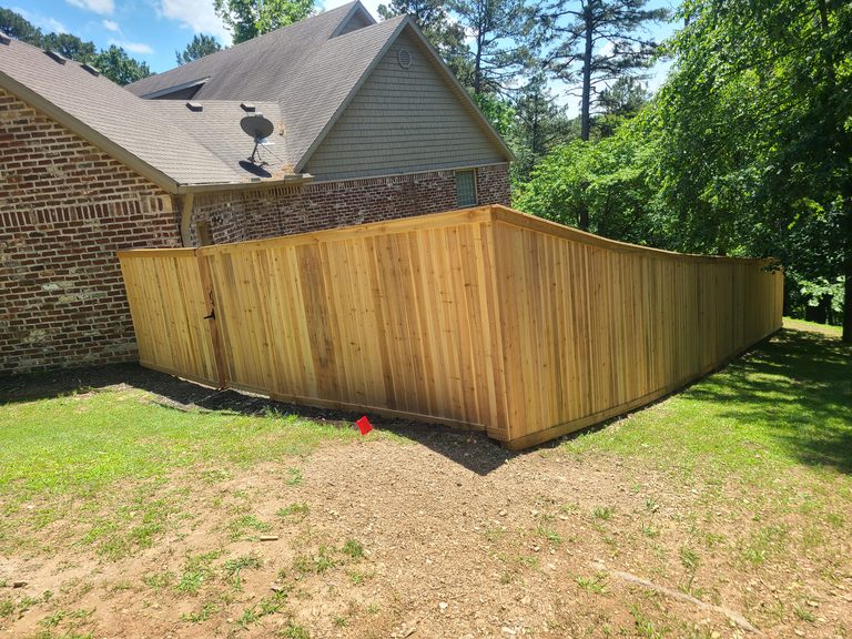 Cedar board-on-board privacy fence wrapping a brick home in Northwest Arkansas