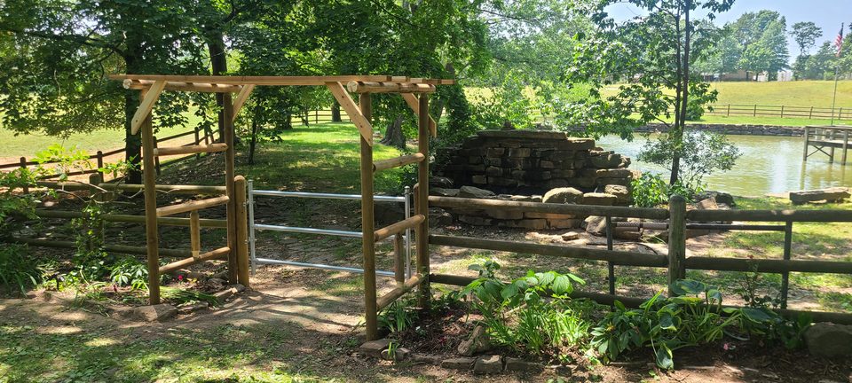 Custom cedar arbor and split-rail fence the Smith family built beside a private pond in Northwest Arkansas