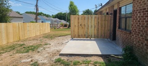 Treated-pine privacy fence beside a new concrete pad in Northwest Arkansas