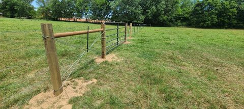 Pipe-and-cable ranch fence with a steel farm gate in a pasture in Northwest Arkansas