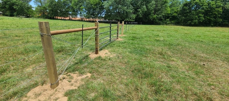 Pipe-and-cable ranch fence with a steel farm gate in a pasture in Northwest Arkansas