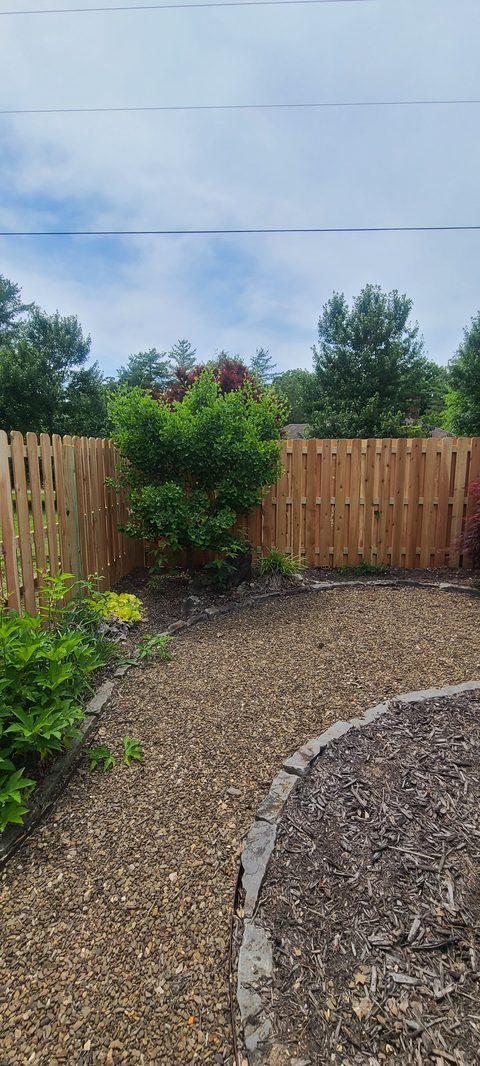 Shadowbox cedar privacy fence behind a landscaped gravel path in Northwest Arkansas