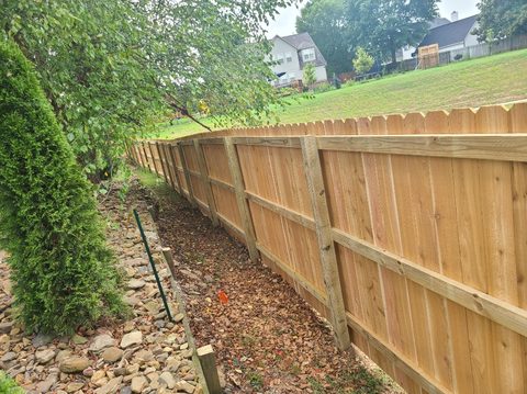 Cedar privacy fence stepped to follow a sloped rock bed in Northwest Arkansas