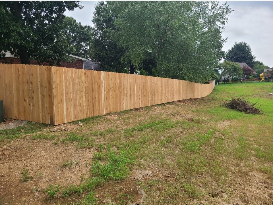 Cedar privacy fence stepping cleanly down a sloped Northwest Arkansas yard